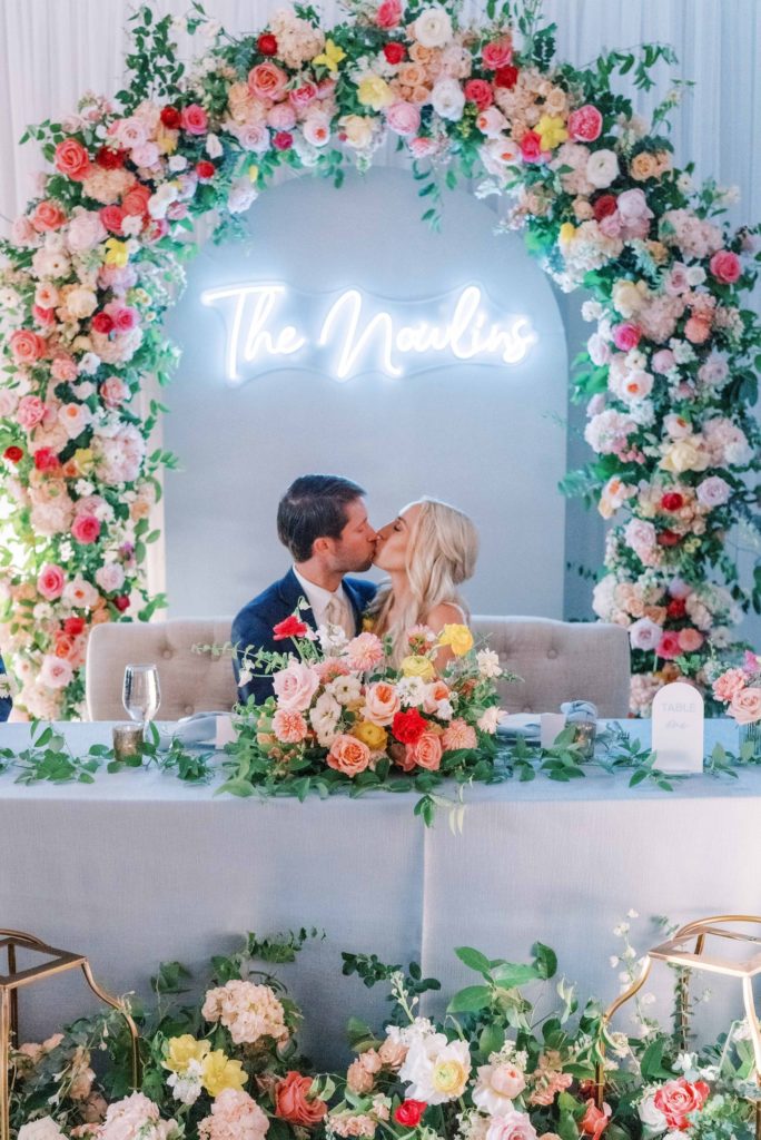 Sweetheart table with colorful floral arch