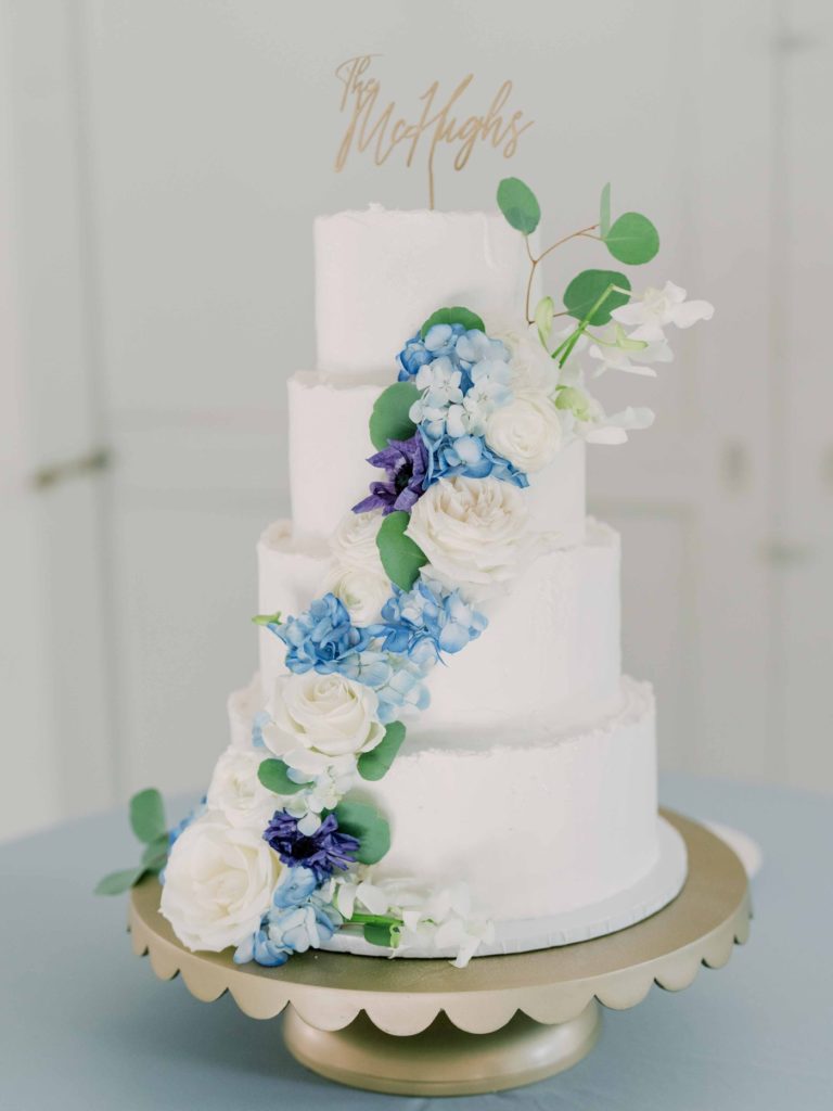 White wedding cake with fresh blue flowers for reception at Spain Ranch