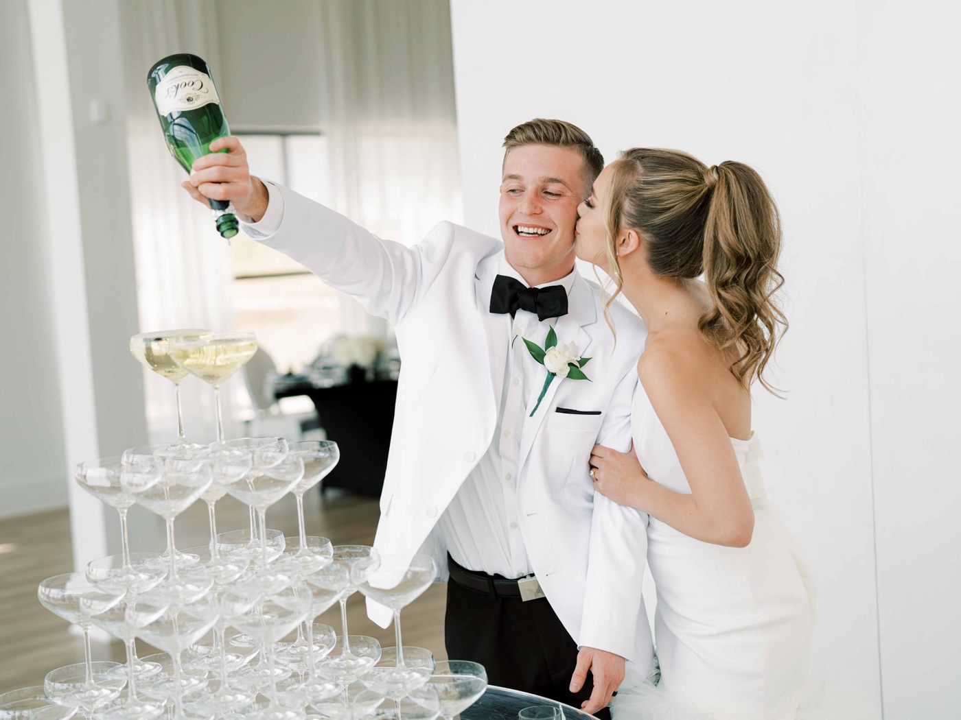 Bride and groom pouring a bottle of champagne into a champagne tower at a styled shoot in Tulsa
