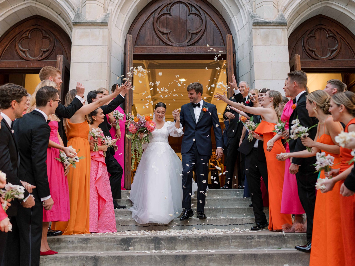 Wedding guests tossing flower petals on a bride and groom exiting their San Antonio ceremony