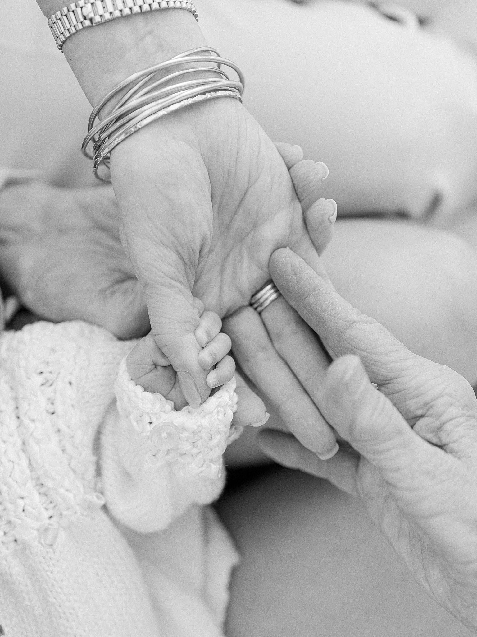 A close-up image of five hands stacked together, from great-grandmother to newborn, representing the strong bond of five generations of women in Tulsa.